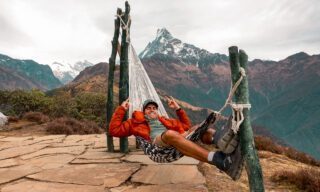 Life Happens Outdoors founder Rami Rasamny relaxing in a hammock on the way to High Camp with Fishtail Mountain in the background during the Mardi Himal trek