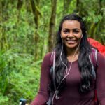 Life Happens Outdoors climber trekking through Kilimanjaro’s rainforest on day one of the Machame Route, smiling en route to Machame Camp.