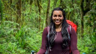Life Happens Outdoors climber trekking through Kilimanjaro’s rainforest on day one of the Machame Route, smiling en route to Machame Camp.