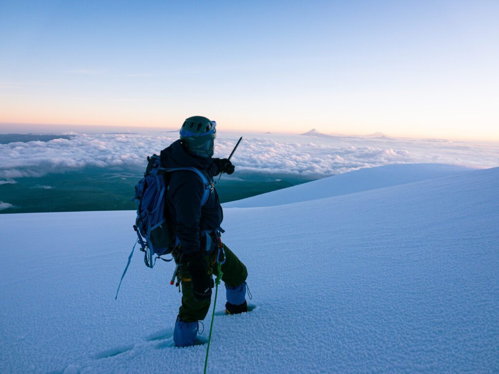 LHO guide Jorge Coronel pointing out Cotopaxi on the horizon from the summit of Chimborazo during the Climb Cotopaxi & Climb Chimborazo Expedition with the Life Happens Outdoors team.