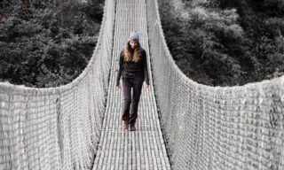LHO member Mariam Hegazi crossing a suspension bridge between Ghandruk and Chomrong during the Annapurna Base Camp Trek with the Life Happens Outdoors team.