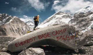 A Life Happens Outdoors Community Member on top of the iconic Everest Base Camp boulder during the LHO Everest Base Camp Trek