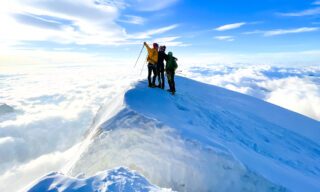 Veteran LHO climber Milly Larmer with her son and IFMGA guide Philippe Genin on the summit of Piramide Vincent, with a sea of clouds beneath during the Spaghetti Tour Expedition Climb Monte Rosa with the Life Happens Outdoors team.