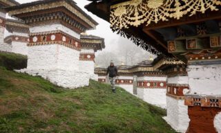 Life Happens Outdoors adventurers walking among the Druk Wangyal Chortens at Dochula Pass, a memorial to fallen soldiers, during a Bhutan adventure tour