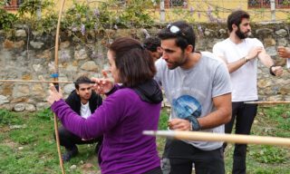 Life Happens Outdoors adventurers trying Bhutanese archery under the guidance of LHO founder Rami Rasamny during a cultural moment on a Bhutan adventure tour