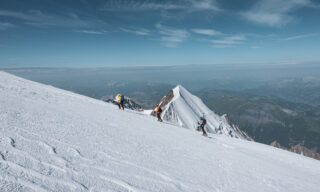 Climbing the Dôme du Goûter with the Aiguille de Bionnassay in the background during the Mont Blanc Summit Climb course with the Life Happens Outdoors team.