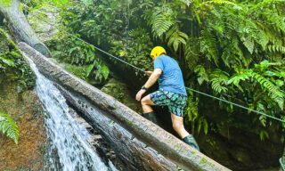 LHO adventurers canyoning through a river gorge in the Amazon, navigating waterfalls and rocky terrain deep in the rainforest.