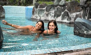LHO adventurers relaxing in the natural hot springs of our handpicked spa accommodation in Baños, surrounded by lush mountain scenery.