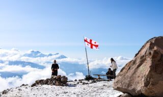 Georgian flag basking in sunshine above the clouds near high camp on Mount Kazbek climb
