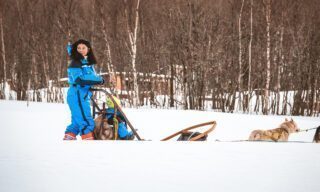 LHO regular Romy Habre dog sledding across the snowy landscapes of Senja Island on a Norway northern lights adventure tour.
