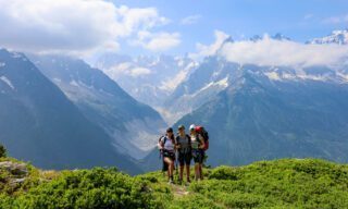 The Life Happens Outdoors team descending from Lac Blanc to Argentière with the Mer de Glace, France's longest glacier, in the background during the Tour du Mont Blanc (TMB).