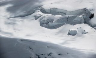 The Life Happens Outdoors team crossing the glacier of the Col de Lys as seen from the summit of the Naso del Lyskamm during the Spaghetti Tour Expedition Climb Monte Rosa.