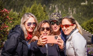 Life Happens Outdoors team members taking a selfie with the Tour du Mont Blanc (TMB) start sign in Les Houches.