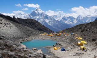 Tents at Lobuche East high camp surrounding a glacier lake, with the majestic Ama Dablam dominating the skyline in the background.