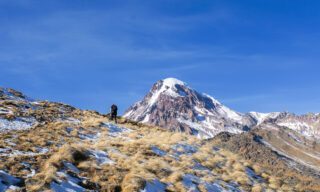 Trekking from Stepantsminda to the Mount Kazbek refuge with the summit of Mount Kazbek visible in the background