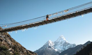 A Life Happens Outdoors hiker on one of the iconic suspension bridges on the Everest Base Camp trek with Ama Dablam in the background