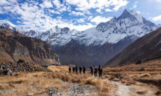The Life Happens Outdoors team descending from Annapurna Base Camp with Machapuchare (Fishtail Mountain) dominating the skyline ahead during the Annapurna Base Camp Trek.
