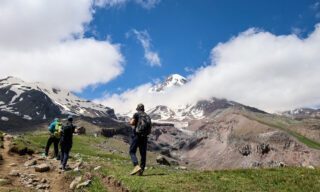 Trekking from Stepantsminda to the Mount Kazbek refuge with the summit of Mount Kazbek visible in the background