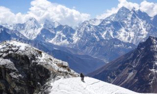 LHO climbers descending from the summit of Lobuche East, with the vast expanse of Himalayan peaks dominating the skyline.
