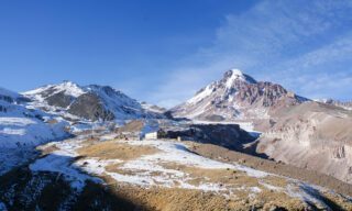 Drone shot of Mount Kazbek towering behind the Gergeti Trinity Church in the Caucasus Mountains