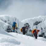 LHO climbers Nada Abanda, Anthony Mezher, and a teammate descending from Cotopaxi crater, surrounded by dramatic glaciers and volcanic terrain in Ecuador.