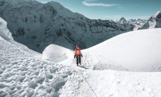 LHO climbers traversing the wavy glaciers of Island Peak under clear skies with panoramic views of the surrounding Himalayas.