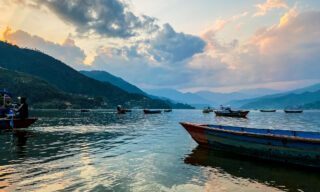 Sunset view of Phewa Lake with wooden rowboats scattered across the water during a Nepal adventure holiday with Life Happens Outdoors