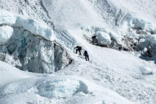 Climbers approaching Island Peak summit on the glacier traverse, framed by breathtaking views of Everest region peaks.
