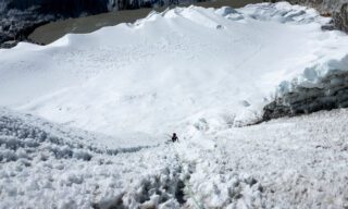 LHO climbers ascending through Island Peak’s headwall above the glaciers, with Imja Lake visible in the distance.