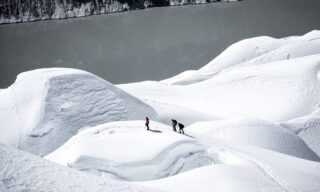 LHO climbers ascending through Island Peak’s wavy glaciers, with Imja Lake visible in the distance.