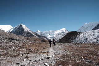 Climbers Roberto David and Haneen Alsliman trekking from Chukhung to Island Peak Base Camp, with the dramatic, free-standing face of Island Peak rising directly ahead.