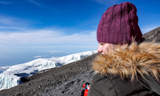 Life Happens Outdoors climber admiring a glacier below Kilimanjaro’s summit, just before reaching the top in perfect blue sky conditions.