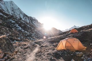 Island Peak Base Camp at sunset, with the last light of the sun peeking over the valley and casting a golden glow on the surrounding peaks.