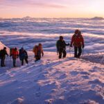 The Life Happens Outdoors team and protagonists of "The Summit Within: A Journey to the Furthest Point on Earth" on the shoulder of Cotopaxi at sunrise, with a sea of clouds below and the giant volcanoes of Ecuador dotting the skyline. The team is led by LHO IFMGA guide Franklin Varela.