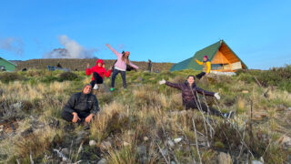 Life Happens Outdoors team relaxing outside Horombo Hut in the short grass vegetation zone during their Kilimanjaro descent.