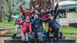 Life Happens Outdoors team with leader Menna Emad at the Machame Gate sign, beginning their Kilimanjaro trek on the Machame Route.