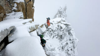 HO climbers traversing a steep ridge beneath the Yellow Tower in snowy conditions on the Climb Ama Dablam Expedition with Life Happens Outdoors.