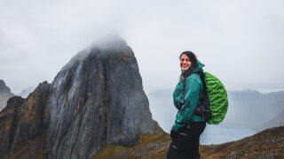 LHO guest Layla Taha standing in front of the dramatic peak of Mount Segla on the island of Senja during the Norway Arctic adventure