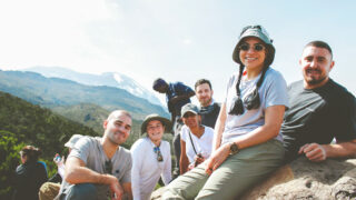 Life Happens Outdoors climbers on the Machame Route, soaking up the sun between alpine forest and short grass zone while trekking from Machame to Shira Camp.