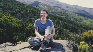 Life Happens Outdoors trekker soaking in the sunshine between the alpine forest and short grass zone on the Machame Route to Shira Camp.