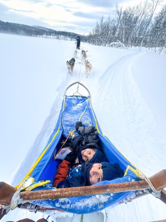 The Doughan family dog sledding on the Arctic island of Senja during the Family Adventures: Chase the Northern Lights with the Life Happens Outdoors team.