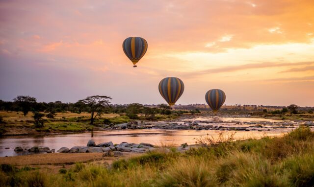 Hot air balloons lifting off at sunrise during the Family Adventure Serengeti Safari with the Life Happens Outdoors team.
