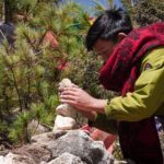 A Sherpa boy placing a rock on a cairn above Namche Bazaar during the Everest Base Camp Trek with the Life Happens Outdoors team.