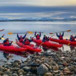 The Life Happens Outdoors team kayaking in the fjords of Norway's Arctic island of Senja during the Chase the Northern Lights adventure.