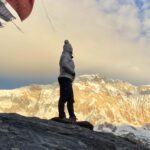 LHOer watching the sunrise on the South Face of Annapurna, deep within the Annapurna Sanctuary, with prayer flags around the stupa during the Annapurna Base Camp Trek with the Life Happens Outdoors team.