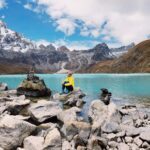Hiker sits across the Gokyo Lakes under perfect blue skies