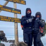 LHO Team Leader Jean Louis Moukarzel and LHO Kilimanjaro guide Saidi at the summit sign of Uhuru Peak on the summit of Mount Kilimanjaro during the Climb Kilimanjaro Expedition with the Life Happens Outdoors team.