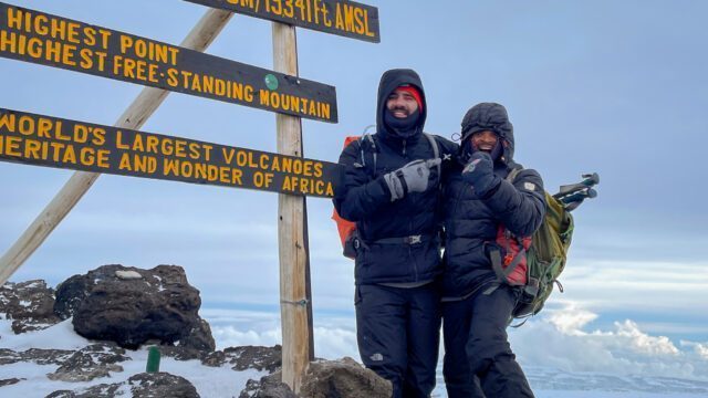 LHO Team Leader Jean Louis Moukarzel and LHO Kilimanjaro guide Saidi at the summit sign of Uhuru Peak on the summit of Mount Kilimanjaro during the Climb Kilimanjaro Expedition with the Life Happens Outdoors team.