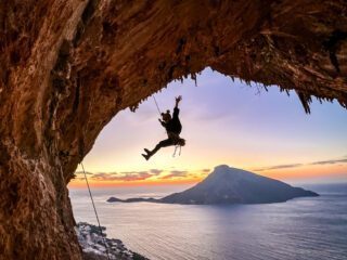 Climbing in the Grande Grotta with incredible sunset light and the sea in the background during the Rock Climbing in Kalymnos adventure with the Life Happens Outdoors team.
