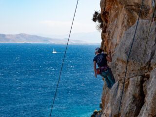 LHOer climbing over the sea on a remote beach only accessible by boat during the Rock Climbing in Kalymnos adventure with the Life Happens Outdoors team.
